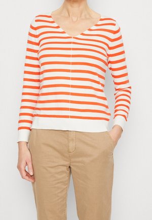 Maglione a maniche lunghe a righe rosse e bianche con scollatura a V, polsini a costine e orlo aderente, abbinato a pantaloni beige.
