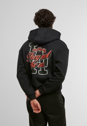 Black hoodie with a large back graphic featuring stylized text and a letter design. Soft fabric and relaxed fit, cuffed sleeves.