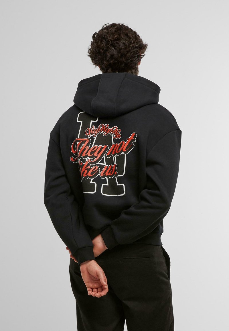 Schwarzer Hoodie mit einem großen Rückendruck, der stilisierte Schriftzüge und ein Buchstabendesign zeigt. Weicher Stoff und lockere Passform, mit Bündchen an den Ärmeln.