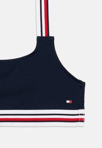 Κοντό μπλουζάκι σε ναυτικό μπλε με λευκές, κόκκινες και μαύρες ρίγες. Διαθέτει ετικέτα με λογότυπο και λείο, ελαστικό ύφασμα. Ρυθμιζόμενες τιράντες.