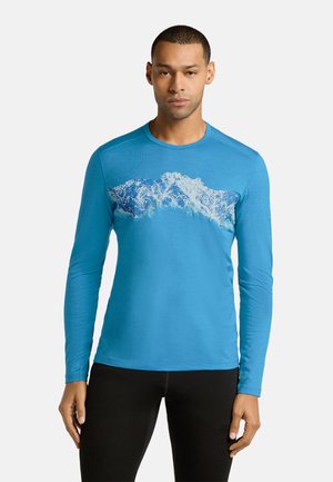 Langärmliges, leuchtend blaues Sportshirt mit einem Berggrafikmuster über der Brust. Hergestellt aus glattem, leichtem Stoff.