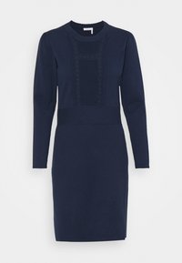 Mörkblå tröjdress med långa ärmar, rund halsringning, texturerad centralpanel, ribbade detaljer och sidoklaffar vid fållen. Tillverkad av ett mjukt tyg.