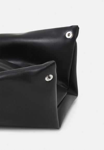 Bolsa de couro preta com um design suave e dobrado, apresentando detalhes em metal prateado e uma superfície texturizada. A bolsa é espaçosa, com uma estrutura aberta.