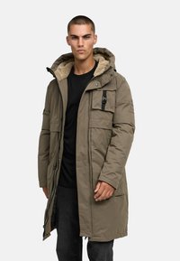 Olivno zelena parka jakna z ali sprednjim kapuco, z zadrgo in gumbom, številnimi žepi in teksturo, zasnovano za toploto in trajnost.