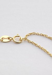 Collana in oro con chiusura a molla rotonda e anelli ovali su uno sfondo grigio chiaro.