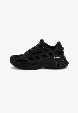 Chaussure de sport noire en mesh et matériaux synthétiques, avec des motifs texturés, une semelle épaisse et un logo de marque blanc contrastant.