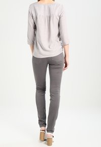 Gråstribet bluse med en afslappet pasform, trekvartærmer og samlet ryg. Matchet med slim-fit grå jeans og lyse hæle sandaler.