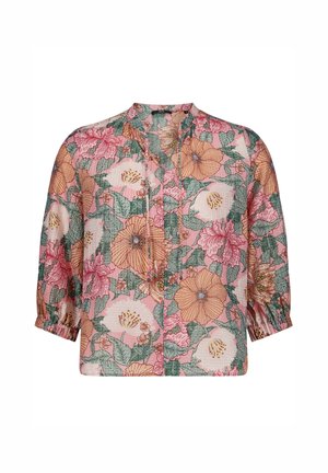 Blouse rose avec imprimé floral orange, blanc et rose, manches trois-quarts avec poignets élastiques, et encolure fendue avec cordons à nouer.