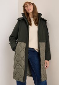Zateplená parka v tmavě zelené barvě s prošívanou světle zelenou spodní částí, se zipem vpředu, kapsami a stojáčkovým límcem.