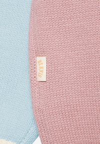 Due campioni di tessuto lavorato a maglia: uno di colore azzurro chiaro e l'altro rosa, con un'etichetta in evidenza con testo dorato in rilievo.