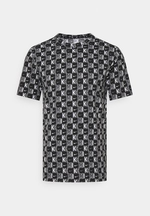 Czarny T-shirt z krótkim rękawem z białym wzorem w formie bloków na całej powierzchni, zawierający napis "NIKE" i małe logo Swoosh ułożone w siatkę.