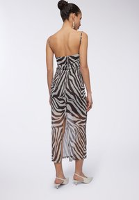 Vestito midi trasparente marrone e grigio con strisce zebra, spalline regolabili e uno spacco sul retro per un tocco in più. Texture liscia.