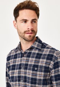 Blau- und braunkarierter Hemd mit Button-Down-Kragen, aus strukturiertem Stoff und mit einer Brusttasche mit Knopfverschluss.