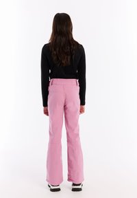 Ružové lyžiarske nohavice s uvoľneným strihom a rozšíreným lemom. Vyrobené z hladkej, odolnej tkaniny. Obsahujú detaily pásu a skryté zipsy.