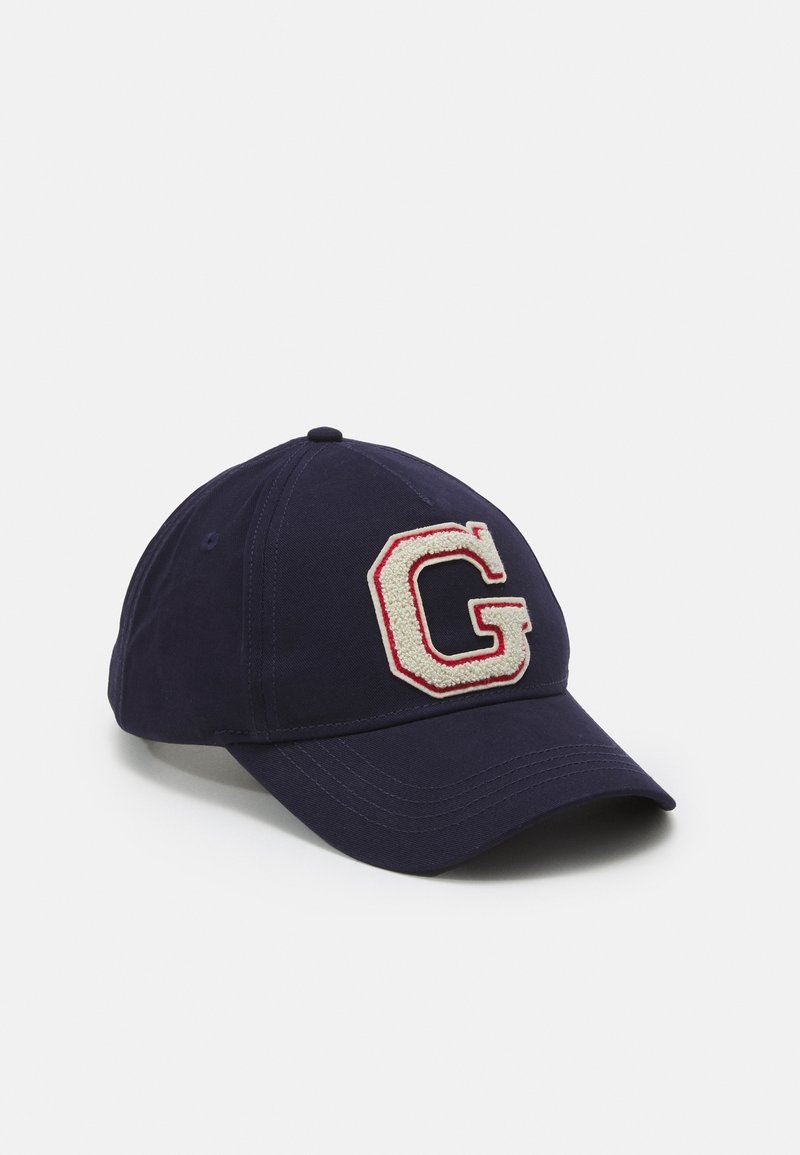Casquette de baseball bleu marine avec une lettre "G" blanche et rouge texturée sur le panneau avant, visière incurvée et œillets cousus.