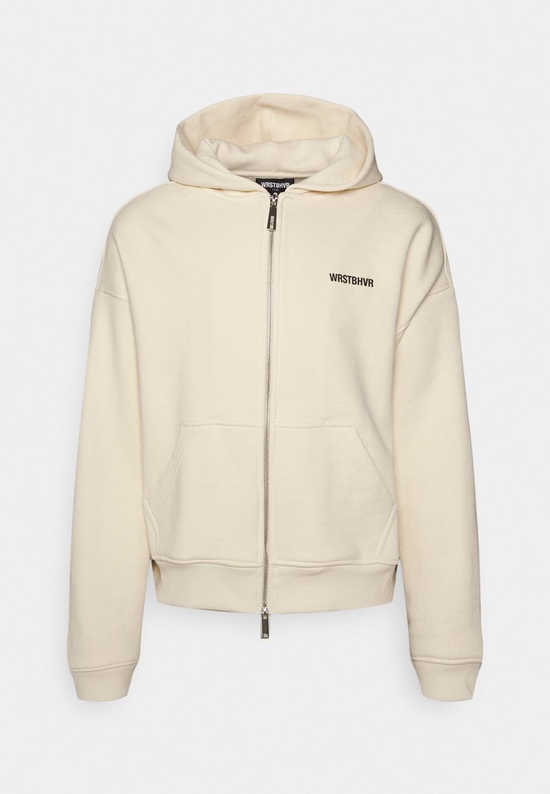 Sweat à capuche crème zippé avec poches avant et logo "WRSTBHVR" sur la poitrine gauche, doté d'une capuche à cordon et de poignets côtelés.