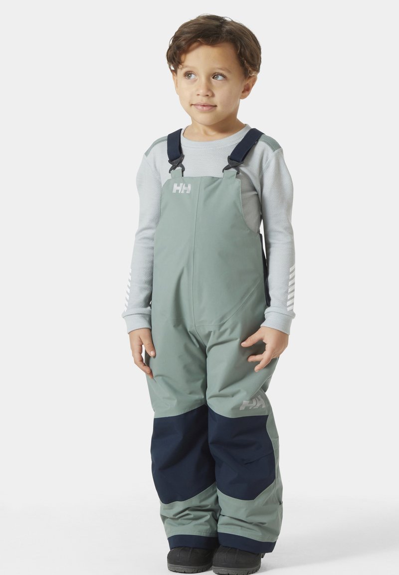 Groene waterdichte tuinbroek met donkerblauwe accenten, verstelbare bretels en versterkte manchetten, gecombineerd met een lichtgrijze lange mouw top.