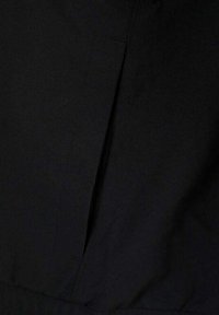 Tela negra con una textura suave que presenta un sutil detalle de costura y un pliegue cosido. Diseño minimalista y elegante sin hardware visible.