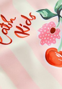 Ein pink- und weiß gestreifter Stoff zeigt eine Illustration einer Kirsche und einer Blüte, mit kräftigen roten und pinken Akzenten sowie dem Text "Catch Kids" in Kursivschrift.