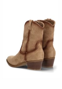 Botines de ante en color beige con un diseño curvado, costuras decorativas y un tacón de madera apilada. Cuenta con un cierre de cremallera y una pestaña para facilitar el calzado.