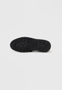 Black rubber shoe sole with textured tread pattern, circular grips, and raised accents for traction. Flat design with no visible branding.