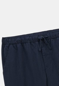 Shorts rayés bleu marine avec une taille élastique et un cordon de serrage. Dotés de poches latérales et d'un tissu doux et texturé.