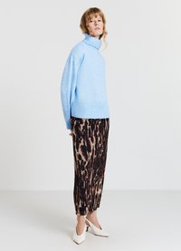 Hellblaues Rollkragenpullover mit strukturiertem Strick, kombiniert mit einem braunen Tiermotivrock und weißen High Heels.