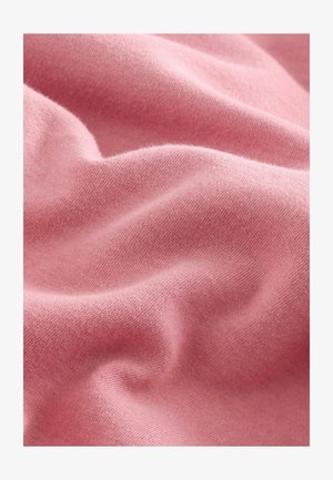 Mjuk rosa tyg med en slät textur, med subtil stretch och fint stickat mönster, som visar försiktiga veck och kurvor.