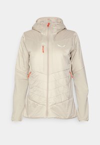 Beige eristetty takki hupulla, jossa on oranssit vetoketjut ja korostukset, vetoketjukiinnitys edessä ja päällikankaassa tikattu pinta. Kevyt muotoilu.