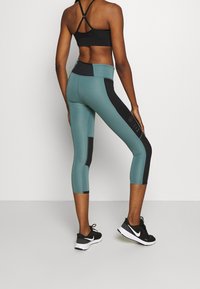 Leggings korkeavyötäröiset, turkoosit mustilla sivupaneeleilla ja logotiedolla. Valmistettu joustavasta materiaalista, jossa on tiukka malli.