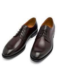Scarpe eleganti in pelle bordeaux scuro con texture liscia, punta affusolata e lacci neri. Presentano un design elegante e un minimo di cuciture decorative.