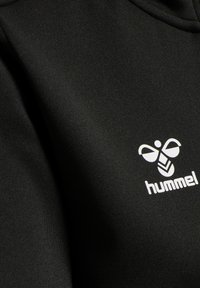Sort stof med en hvid stiliseret bi-logo og ordet "hummel" trykt på det.