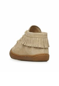 Scarpa per bambino in suede dorato con dettagli in frange sul retro, punta rotonda e suola in gomma marrone texturizzata. Presenta lacci per una vestibilità sicura.