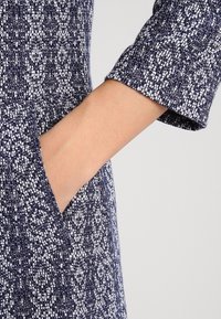 Tessuto per abito in navy e bianco con una trama sottile. Presenta maniche corte e una tasca laterale integrata nel design.