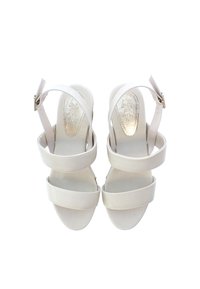 Beige remsandaler med en slät, matt yta; har en smäcker klack, ankelrem med spänne och vadderad fotbädd med en subtil logotyp.