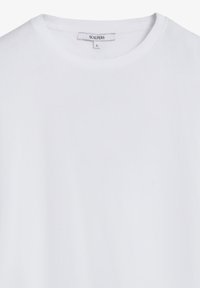White cotton T-shirt with a round neck, short sleeves, and a tag labeled "SCALPERS." Smooth texture and solid color. Size "S."