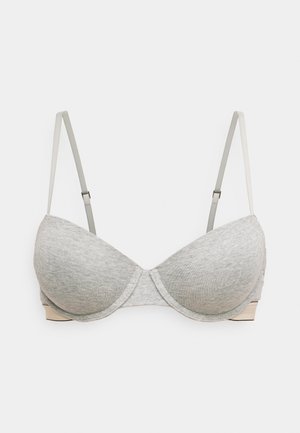 Soutien-gorge gris avec des coques moulées, des bretelles réglables et une texture lisse. Présente une couture subtile le long des bords et une bande dans une couleur complémentaire.