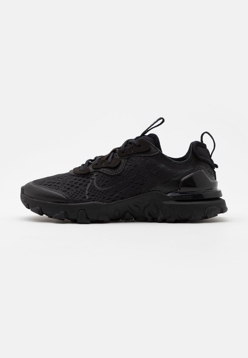 Zapatilla deportiva negra con parte superior de malla, puntera texturizada y suela acolchada. Presenta un talón redondeado y ojales reforzados para los cordones.