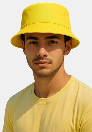 Gelber Fischerhut mit breiter Krempe aus glattem Stoff. Dazu ein passendes gelbes T-Shirt, lässig getragen.