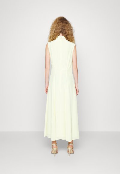 Abito giallo senza maniche, realizzato in tessuto leggero, con una vita arricciata e un colletto finto con dettaglio dei bottoni sulla schiena.
