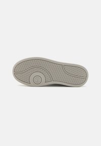 Sole di scarpa grigio chiaro con un motivo testurizzato, caratterizzata da un logo arrotondato. Materiale liscio e resistente con una leggera curvatura e un design ergonomico.
