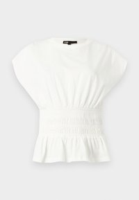 Blouse blanche à manches courtes avec épaules larges, taille élastique froncée et bas peplum, sur un fond clair uni.