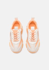 Zapatillas blancas y melocotón con material de malla y sintético. Presentan un diseño deportivo, cordones, interior acolchado y suela texturizada.