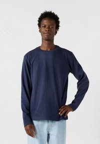 Marineblauwe lange mouwen t-shirt van katoen, met een ronde hals en een relaxed fit. Draagt met lichtblauwe jeans, minimalistisch ontwerp en zonder patronen.
