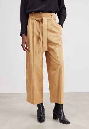 Kaki wijde broek met een tailleband met ceintuur, zijzakken en een gladde textuur, gecombineerd met zwarte enkellaarsjes.