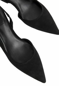 Décolleté in suede nero con punta affusolata, interno liscio, lati bassi e silhouette elegante. Nota per il suo design minimalista.