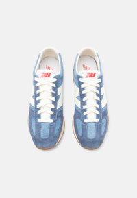 Sneaker blu in suede con accenti bianchi, caratterizzate da una finitura texturizzata, design con lacci e suola in gomma. Logo rosso sulla linguetta.