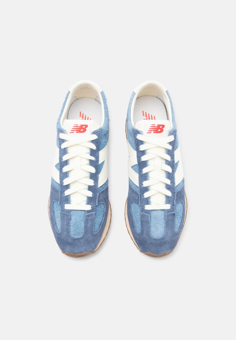 Blaue Wildleder-Sneaker mit weißen Akzenten, ausgestattet mit einer strukturierten Oberfläche, Schnürdesign und Gummisohle. Rotes Logo auf der Zunge.