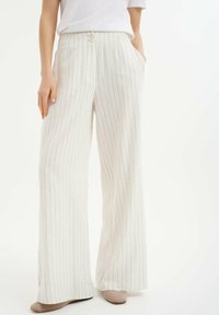 Wijdvallende broek in lichtbeige stof met subtiele verticale strepen, voorzien van een hoge taille, knopen en zijzakken.