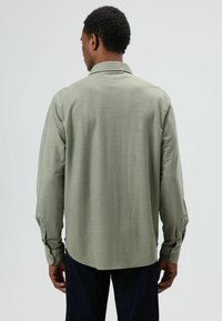 Lichtolijfgroen overhemd met lange mouwen, een kraag, een achterplooi en manchetten met knopen, gemaakt van zachte stof met een gladde textuur.